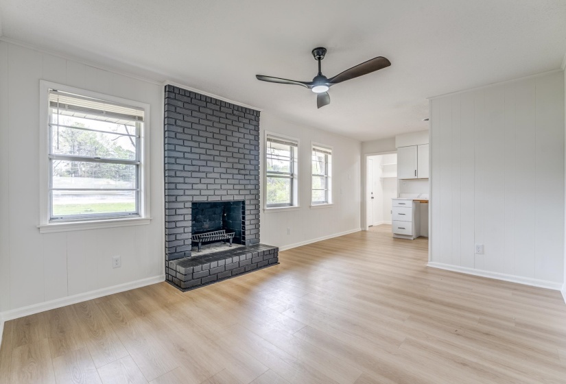 Unfurnished living room with a ceiling fan, a fireplace, and light wood-style flooring