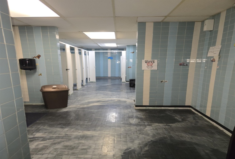 Hallway with a drop ceiling and tile walls