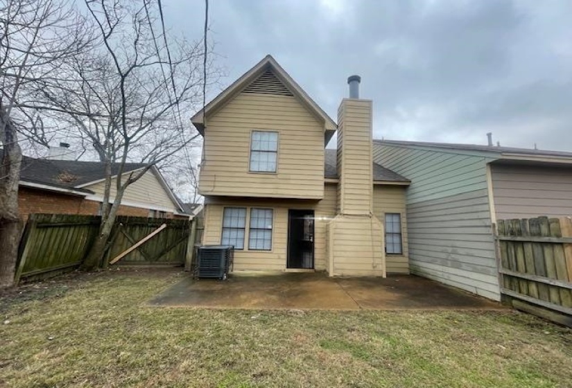 Back of house featuring a fenced backyard, a chimney, a patio, and a gate