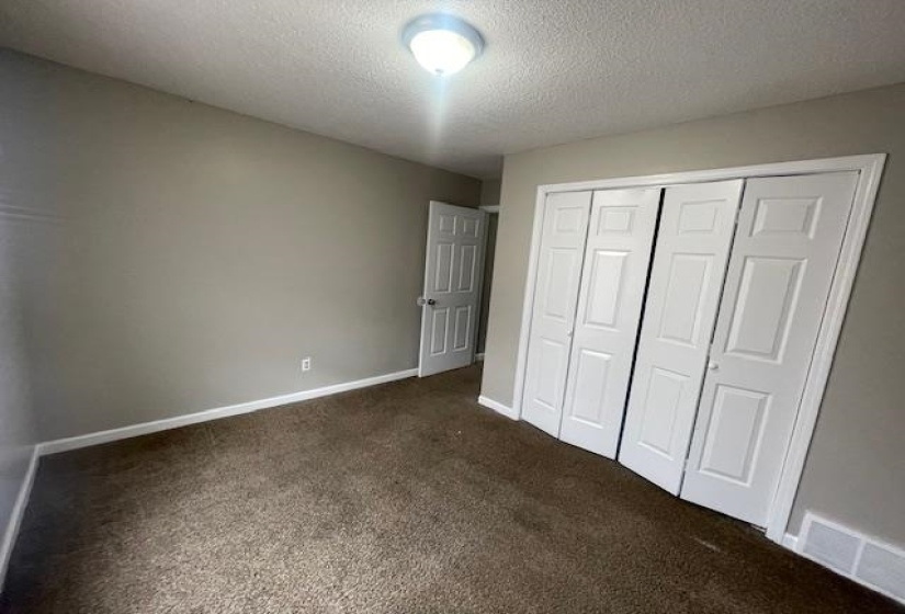 Unfurnished bedroom with a closet, dark carpet, and a textured ceiling