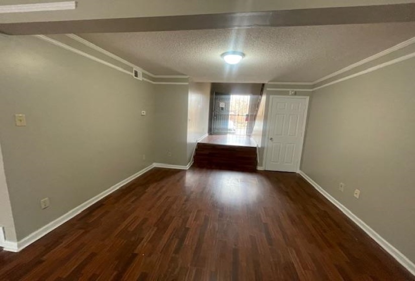 Unfurnished room featuring a textured ceiling, dark wood finished floors, and crown molding