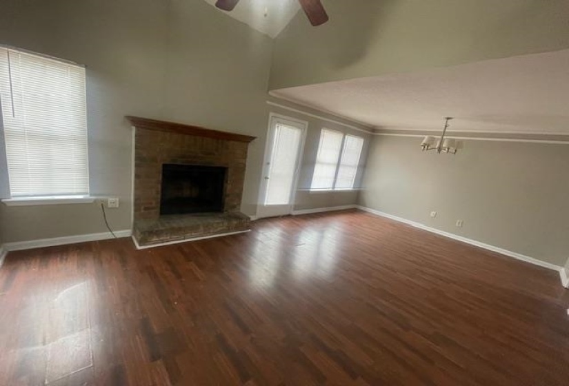 Unfurnished living room with a ceiling fan, dark wood finished floors, a fireplace, vaulted ceiling, and hanging lights