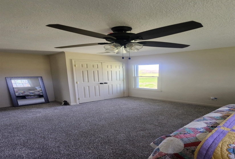 Unfurnished bedroom with carpet, a closet, a textured ceiling, and a ceiling fan