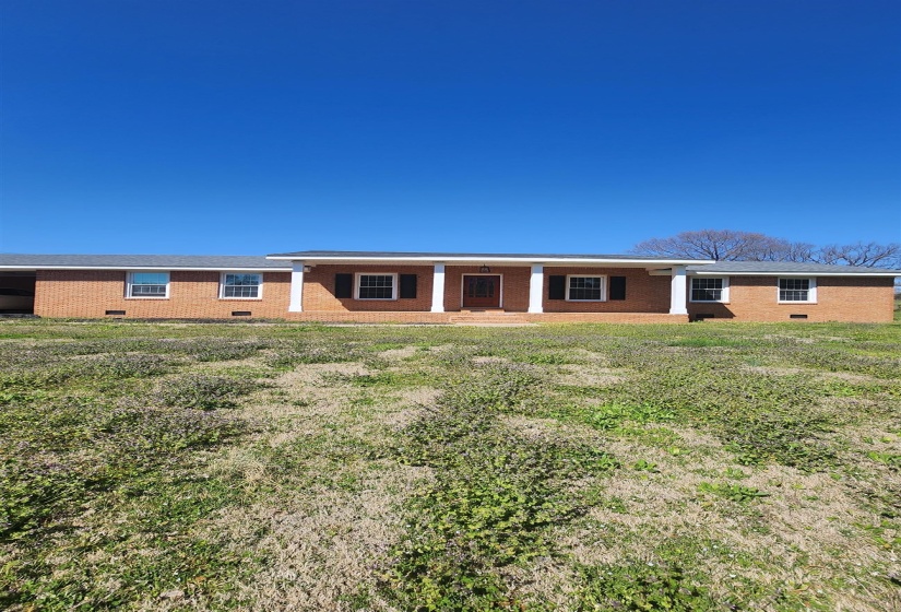 Back of property with a lawn, brick siding, and covered porch