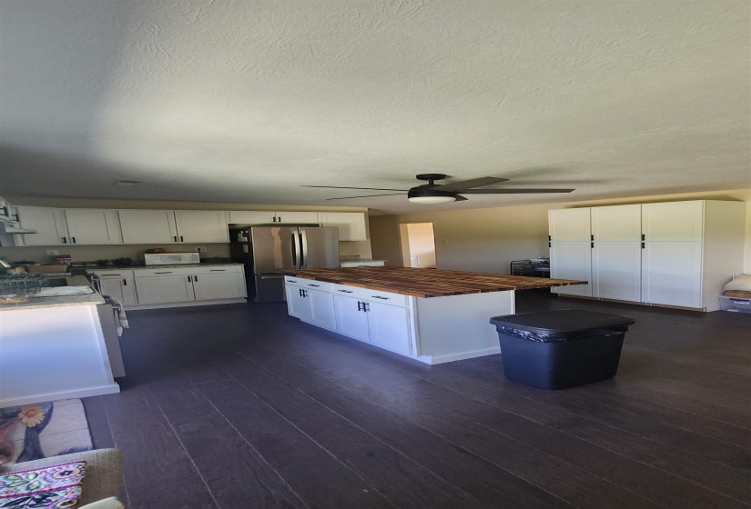 Kitchen featuring wood counters, dark wood-style floors, white cabinetry, freestanding refrigerator, and a center island