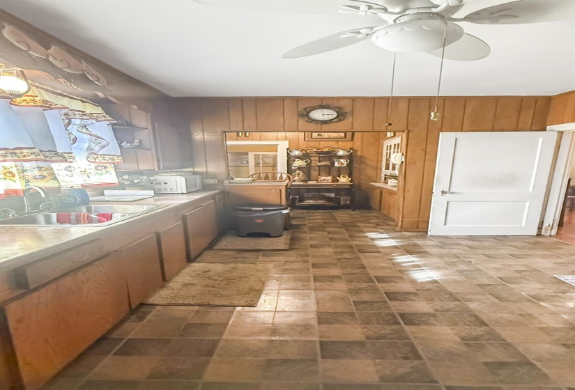 Kitchen featuring ceiling fan, wooden walls, light countertops, wood finish cabinets, and white microwave