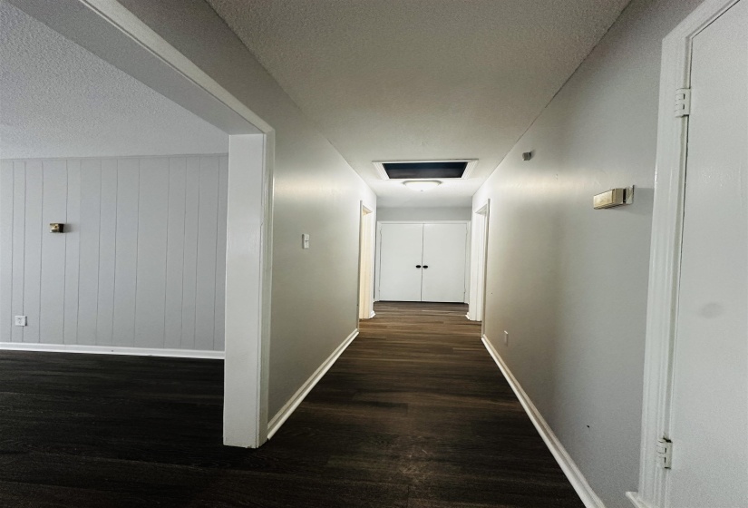 Hall featuring a textured ceiling, dark wood-style floors, and wood walls