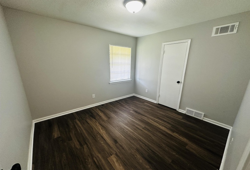 Empty room with dark wood finished floors and a textured ceiling