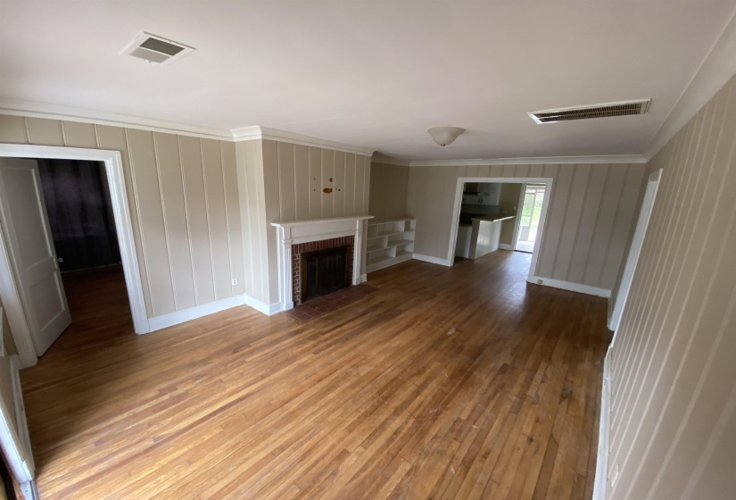 Unfurnished living room with wood-type flooring, ornamental molding, and a fireplace