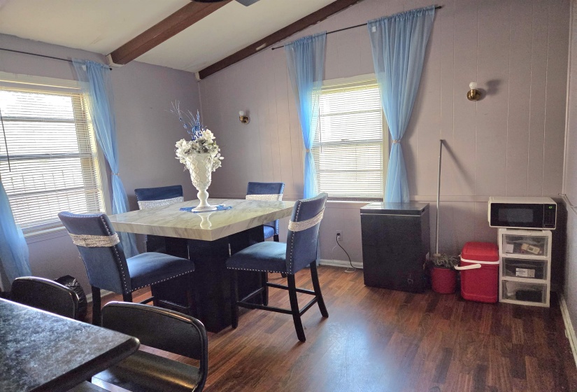 Dining space with dark wood-style floors and lofted ceiling with beams