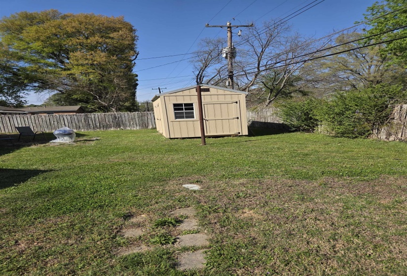 Fenced backyard featuring a shed