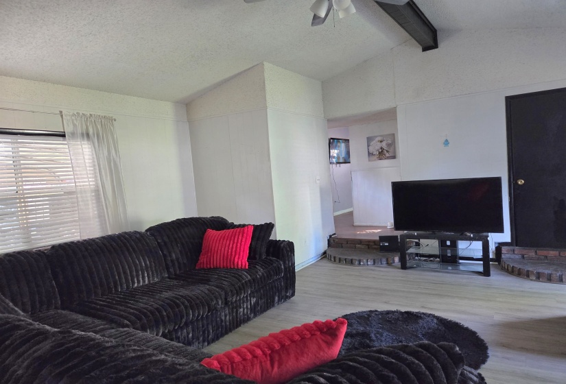 Living area featuring wood finished floors, ceiling fan, and beam ceiling