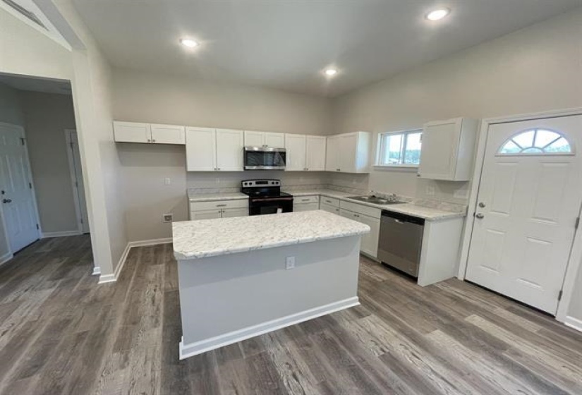 Kitchen featuring white cabinetry, light stone counters, stainless steel appliances, and a center island
