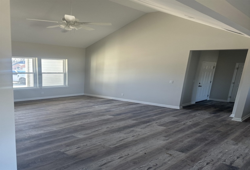 Unfurnished room featuring dark wood-type flooring, ceiling fan, and high vaulted ceiling