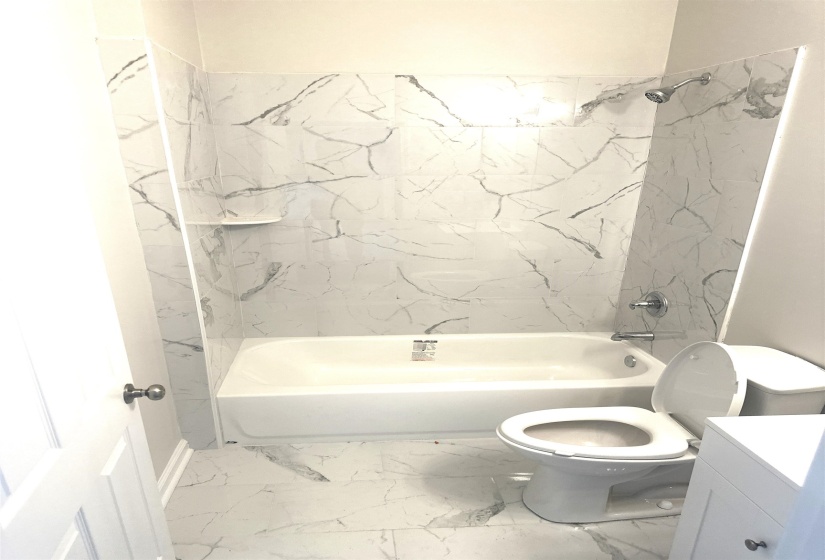 Full bathroom featuring vanity, tiled shower / bath combo, and toilet