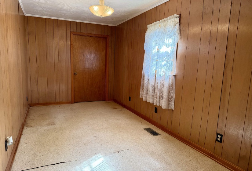 Spare room featuring light floors, wooden walls, and crown molding