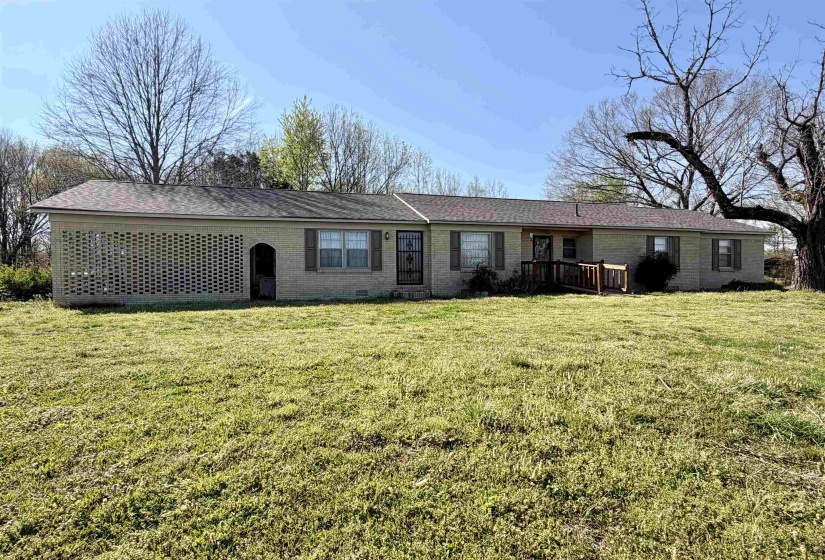 Rear view of house with brick siding, a yard, and a shingled roof