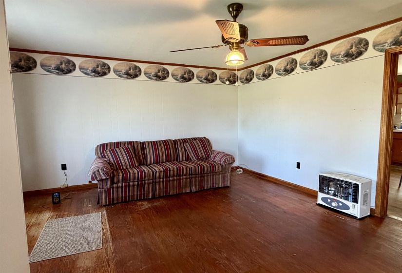 Sitting room with heating unit, dark wood-type flooring, a ceiling fan, and ornamental molding