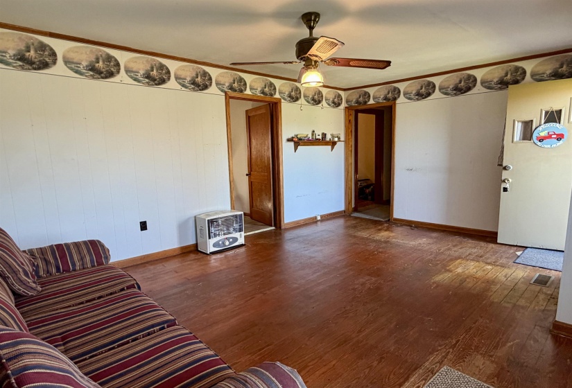 Living room featuring wood finished floors, heating unit, and ceiling fan