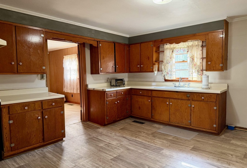 Kitchen featuring wood finish cabinets, light countertops, light wood-style floors, and crown molding