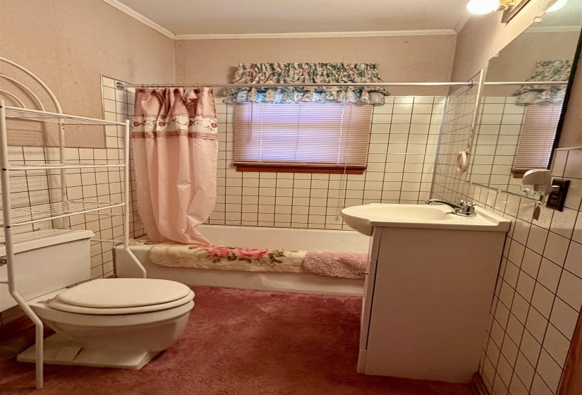 Bathroom featuring tile walls, shower / bath combo, vanity, and ornamental molding