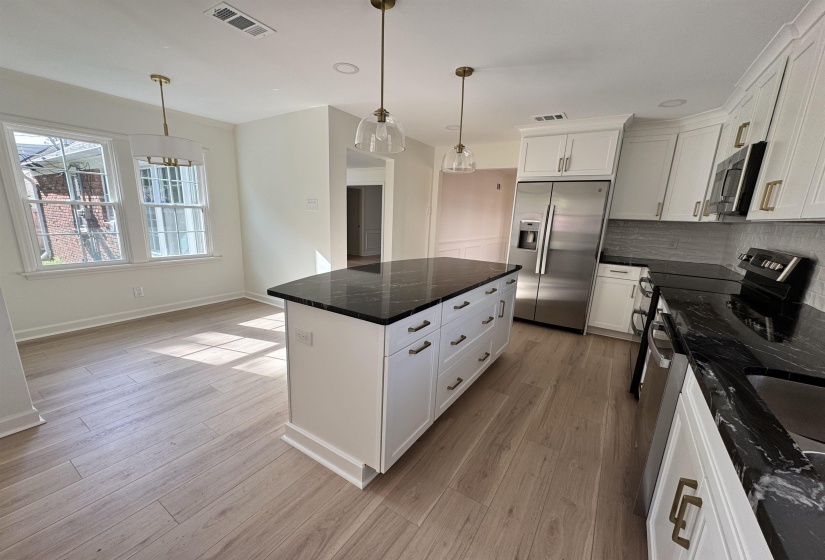 Kitchen featuring light wood-style flooring, modern backsplash, visible vents, appliances with stainless steel finishes