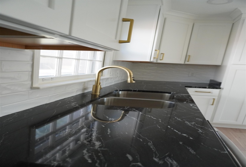 Kitchen featuring modern clean backsplash, white cabinetry, a sink, and granite countertops