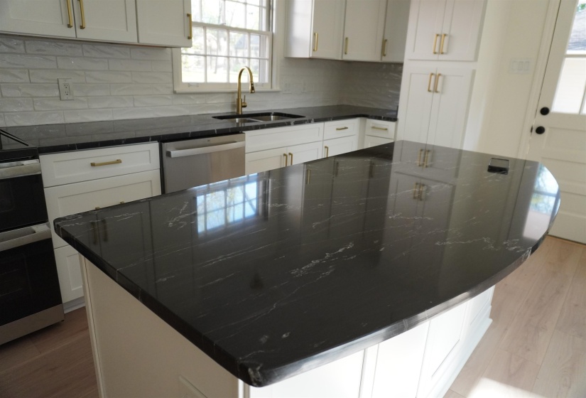 Kitchen with white cabinetry, a sink, stainless steel appliances, a kitchen island, and backsplash