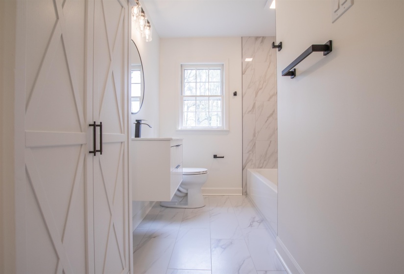 Full bath featuring baseboards, toilet, shower / bathing tub combination, vanity, and marble finish floor