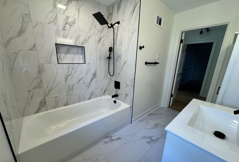 Full bath with visible vents, baseboards, a sink, marble finish floor, and bathing tub / shower combination