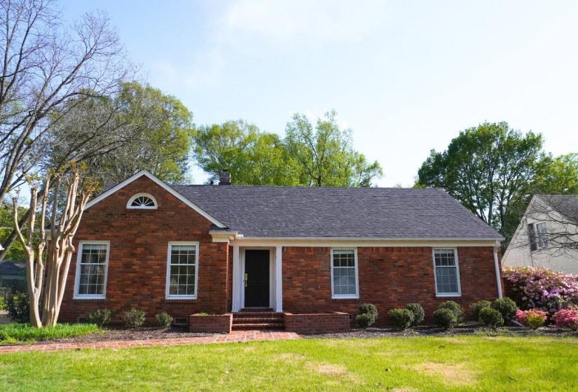 Ranch-style house featuring a landscaped front yard, brick siding, a chimney, and a shingled roof