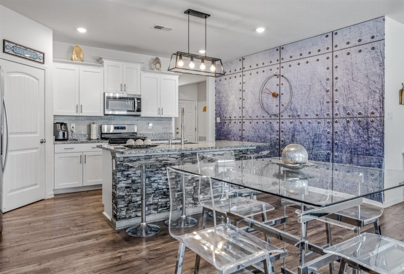 Kitchen with white cabinets, dark wood-style flooring, a center island with sink, and stainless steel appliances