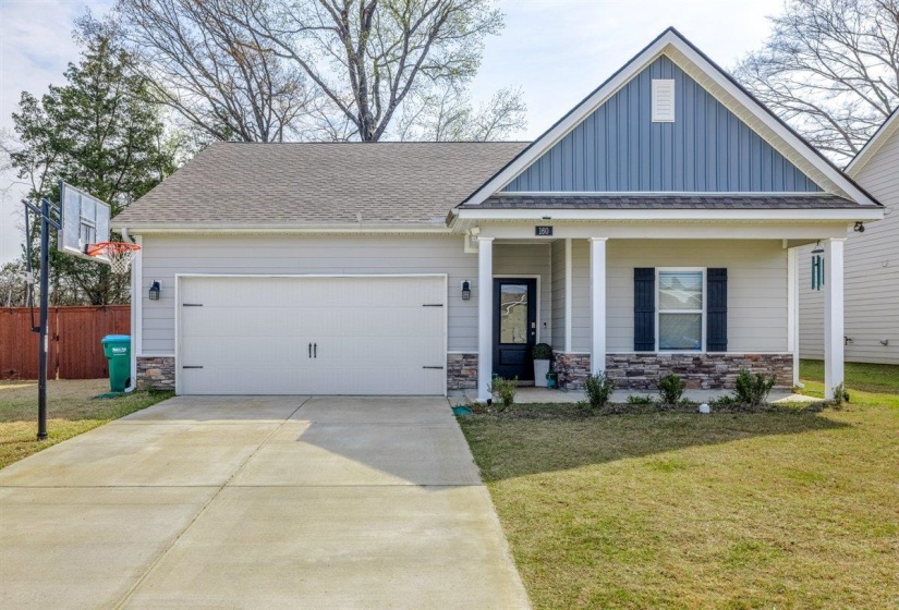 View of front facade with stone siding, a garage, a porch, concrete driveway, and board and batten siding
