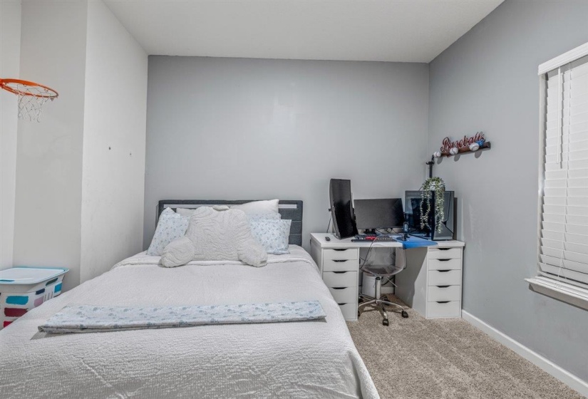 Bedroom with light colored carpet and an office area