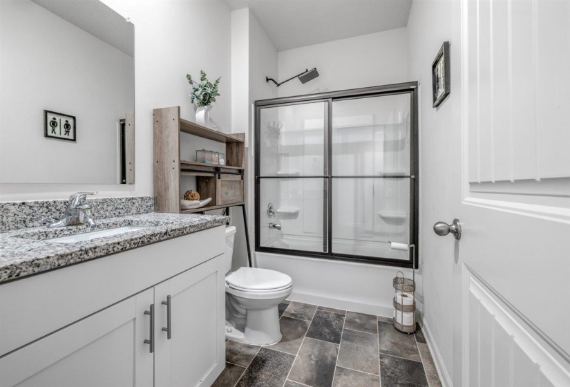 Bathroom with vanity, combined bath / shower with glass door, and stone finish flooring