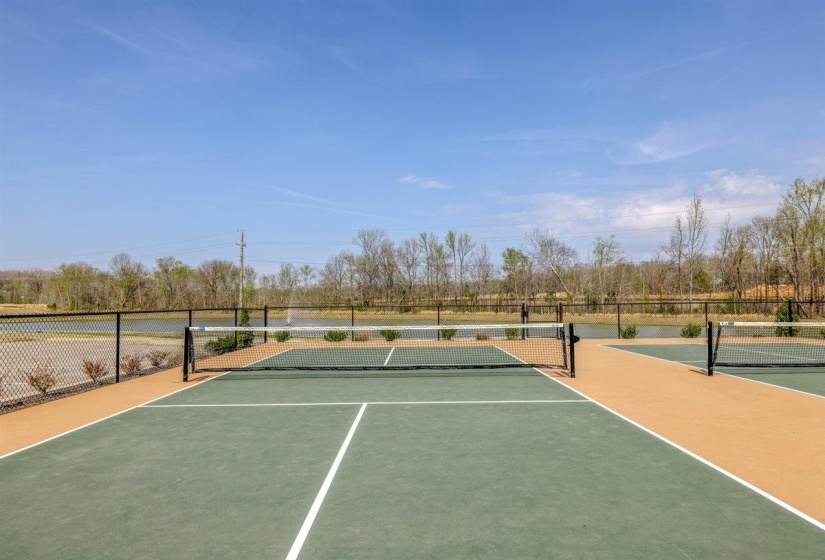 View of tennis court featuring view of wooded area