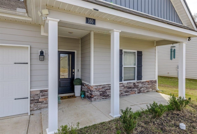 Doorway to property with covered porch, stone siding, board and batten siding, and a garage