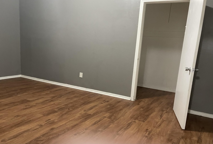 Spare room featuring dark wood-style floors and baseboards