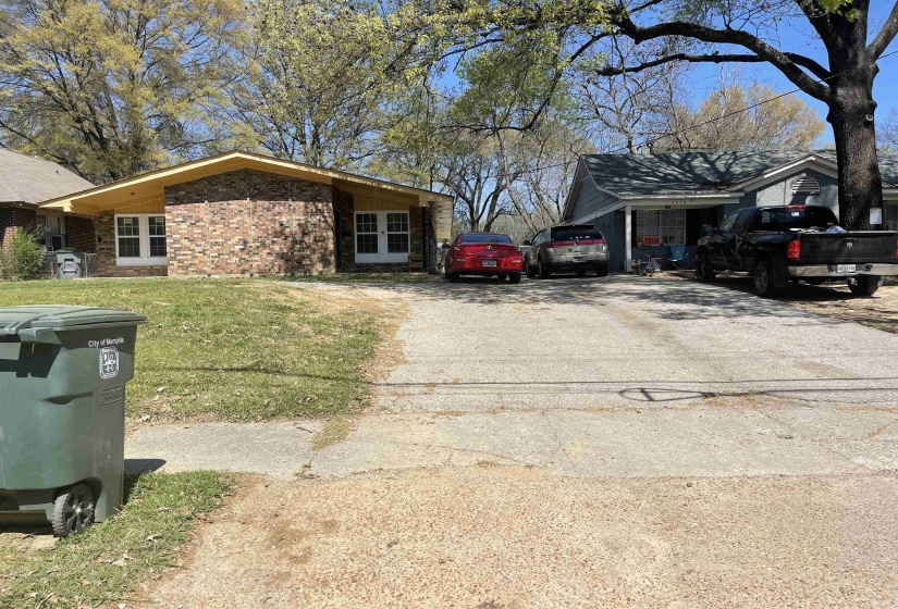 View of side of home featuring brick siding, driveway, and a yard