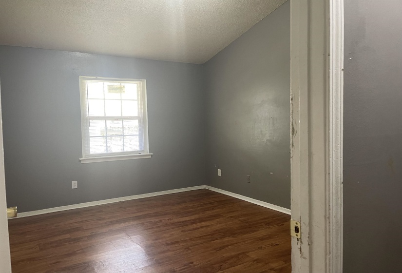 Empty room with a textured ceiling and dark wood-style flooring