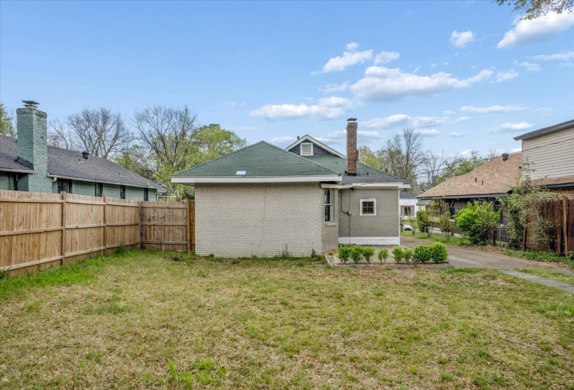 Rear view of house with a fenced backyard, brick siding, and a chimney