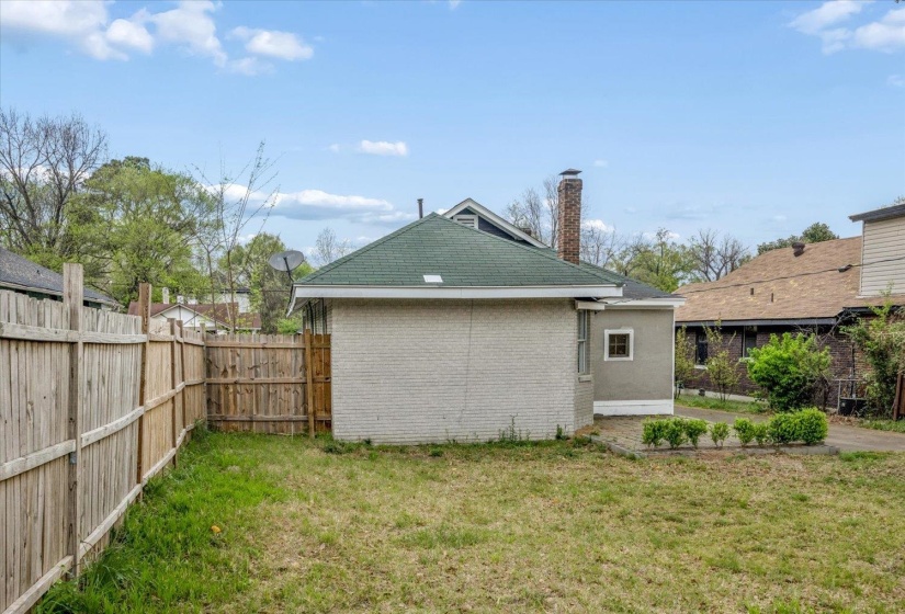 Back of house featuring a fenced backyard, a chimney, and brick siding