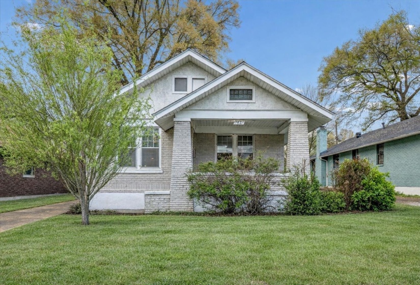 View of front of property with brick siding, a front lawn, and a porch