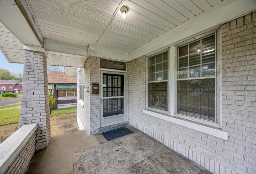 View of exterior entry with covered porch and brick siding
