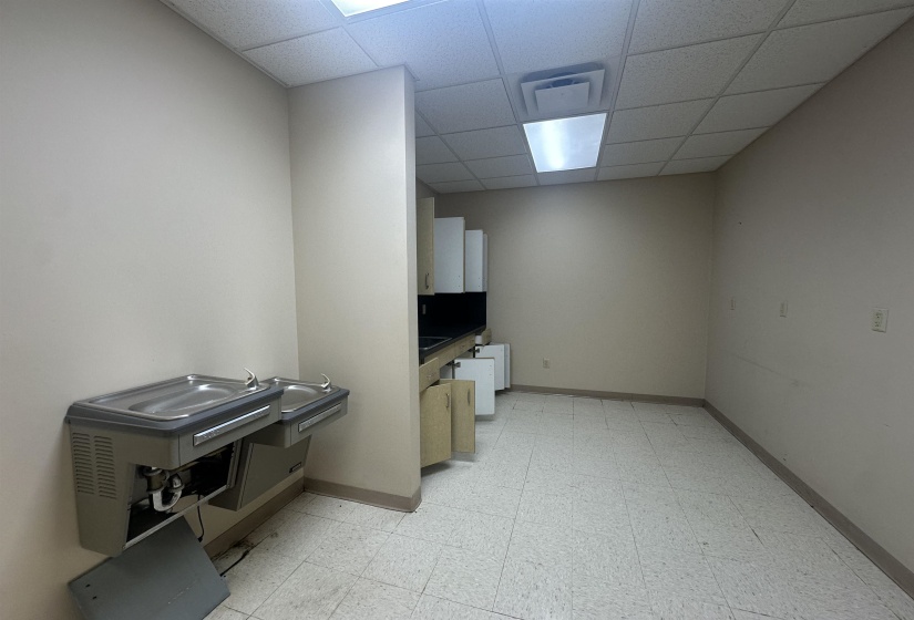 Interior space featuring baseboards, a drop ceiling, and light floors