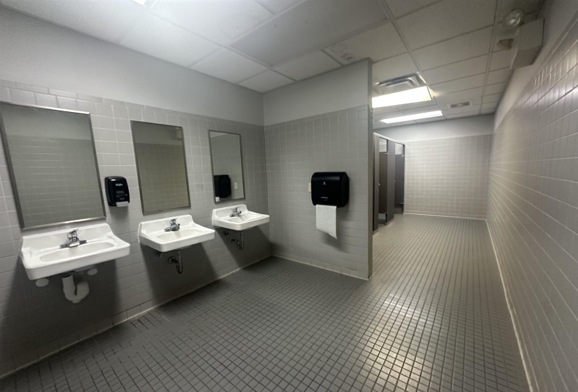 Full bath featuring two sinks, a drop ceiling, tile patterned flooring, and tile walls