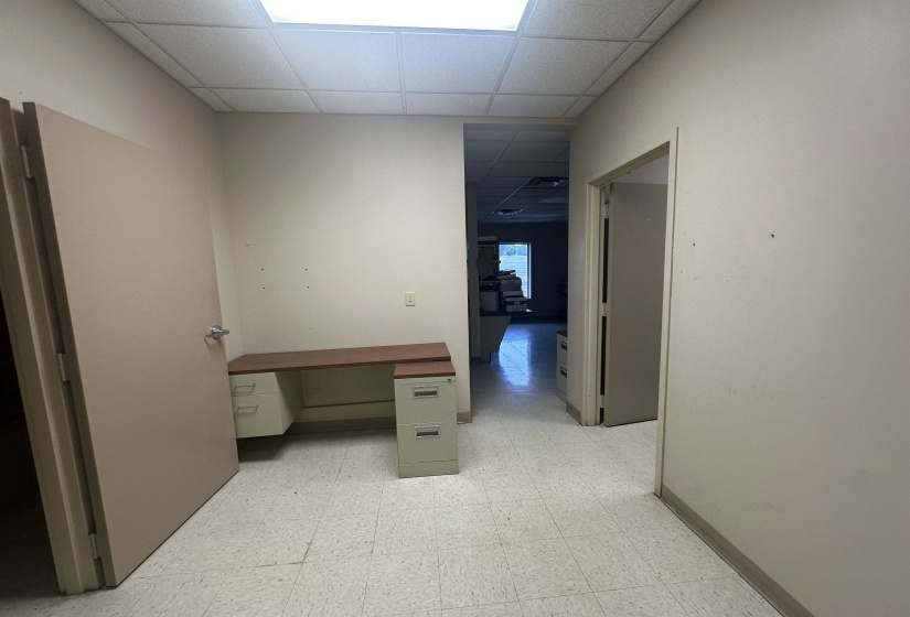Interior space featuring a paneled ceiling, baseboards, and light floors