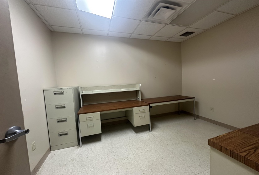 Unfurnished office with light floors, a paneled ceiling, visible vents, and baseboards