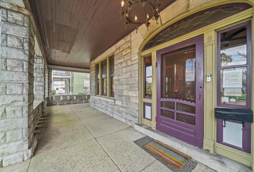 View of exterior entry featuring covered porch and stone siding