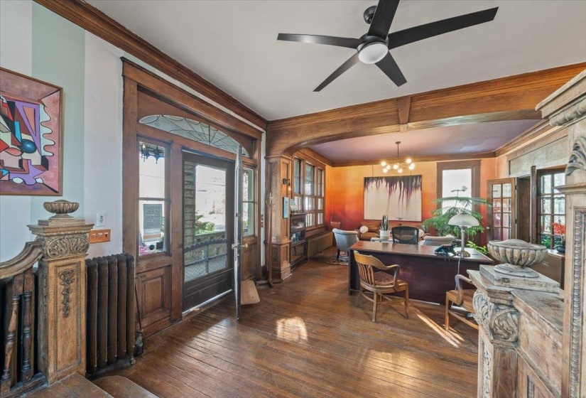 Office area with dark wood finished floors, a ceiling fan, a chandelier, ornamental molding, and radiator